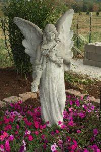 angel statue in pink and purple flowers in a metal trellice