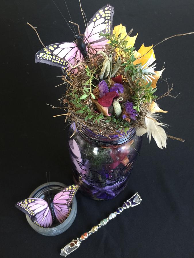 jar of flowers with pink butterfly and a small crystal wand